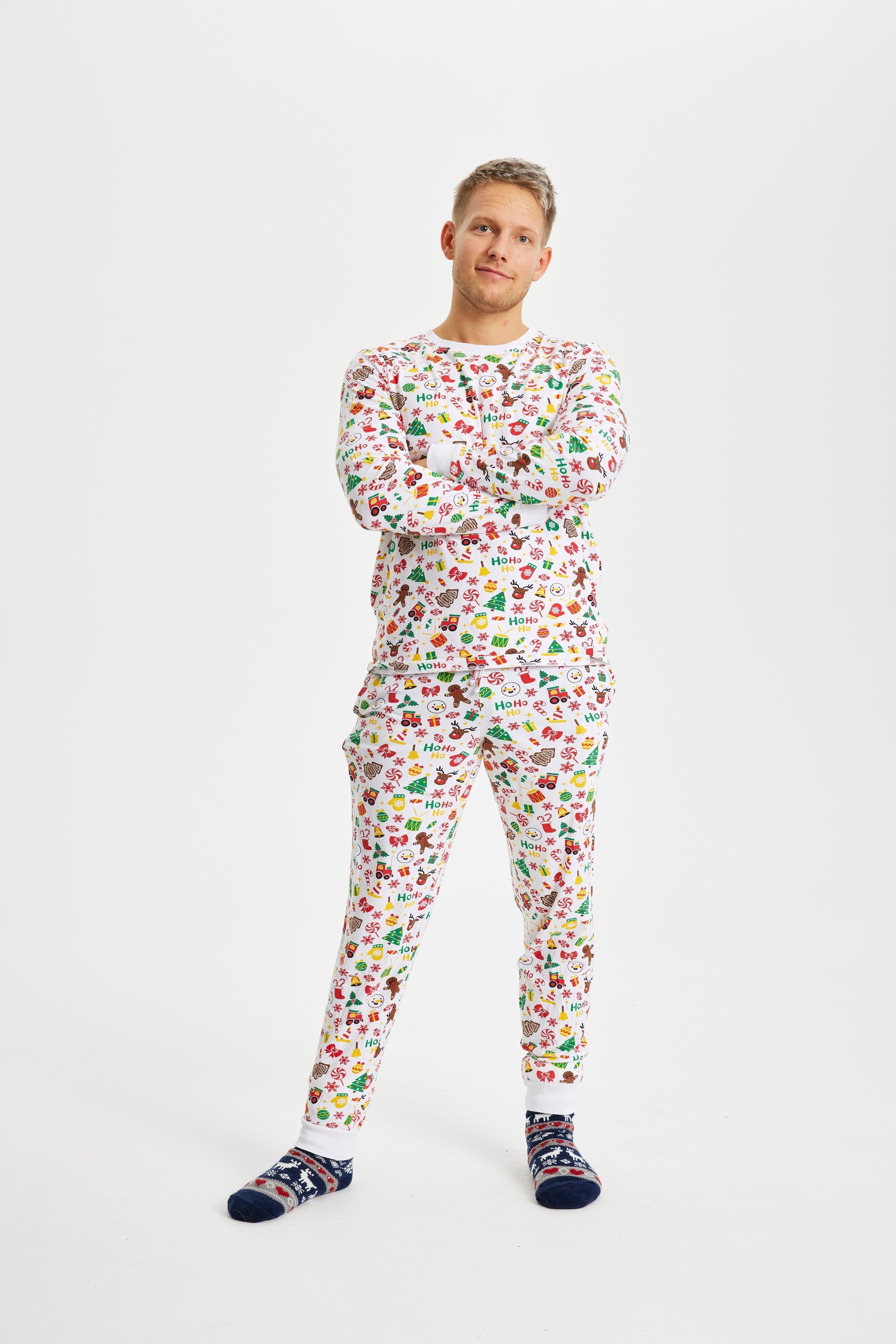 Un homme aux bras croisés portant un pyjama de Noël blanc.